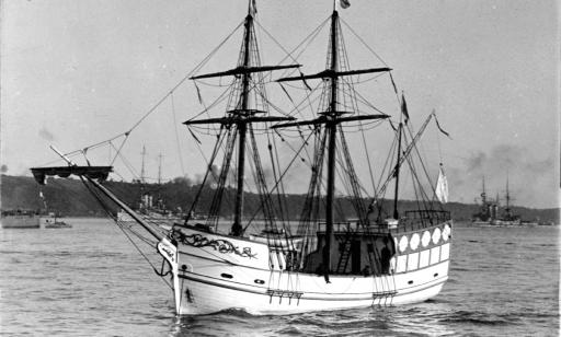 Close-up view of an ornate galleon sailing on the river, with other ships behind it near the distant shore.