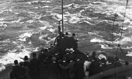 Around 30 tourists stand at the prow of a steamboat looking at the white waters of the Lachine Rapids.