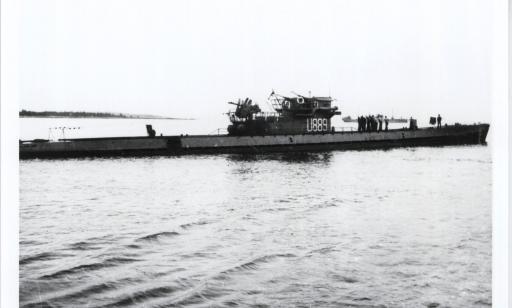 Black and white photo of a German submarine at the surface. Its number is written in white on the turret.