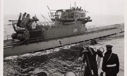 Sailors on a Royal Canadian Navy ship prepare to throw a cable toward a submarine.