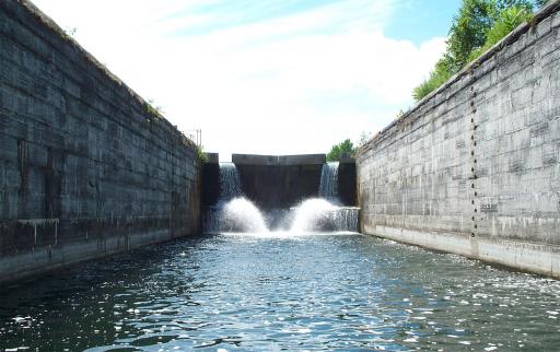 Photo taken from inside the chamber of a lock with its gates closed. The water level is low and the walls are visible.