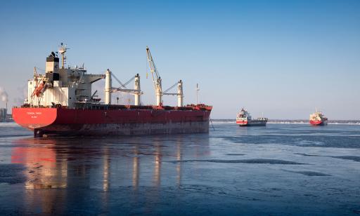 Three cargo ships at anchor on the St. Lawrence. Heavy lifting gear can be seen on the ship in the foreground.