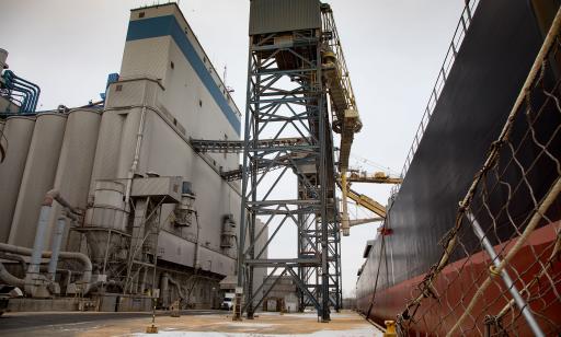 Partial view of a cargo ship's hull and the wharf with its silos and two mobile towers used to unload ships.