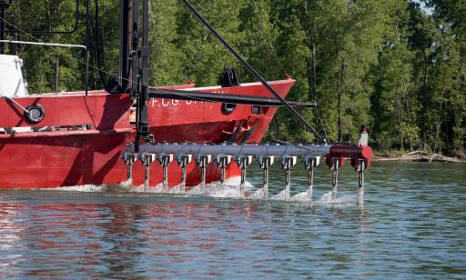 Close-up view of the starboard side of a red and white ship, showing a pole with sensors entering the water.