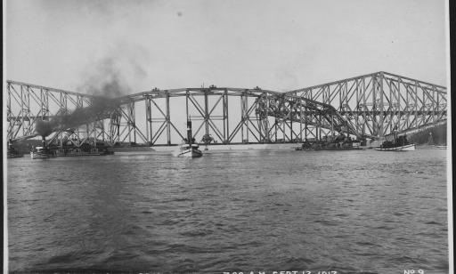 Des remorqueurs soutiennent la partie centrale du pont avant qu’elle soit élevée pour être reliée aux deux autres sections.