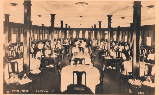 Dans une salle, décorée avec des colonnes et un plafond à caissons, on voit des bouquets sur chacune des nombreuses tables.