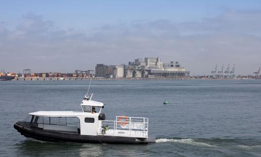 Un homme navigue dans un petit bateau à moteur pneumatique dont le devant est recouvert d’un toit et l’arrière est ouvert. 