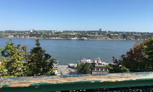 View looking down at a moored ferry. On the other side of the river, buildings and another ferry can be seen.