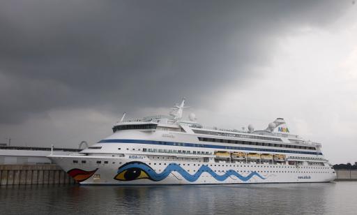 A cruise ship with a white hull, a red and orange mouth on its prow and a yellow eye on its side.