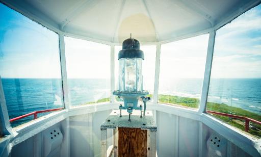 A lamp on a stand inside the lantern. Through the windows, we can see water stretching out to the horizon.