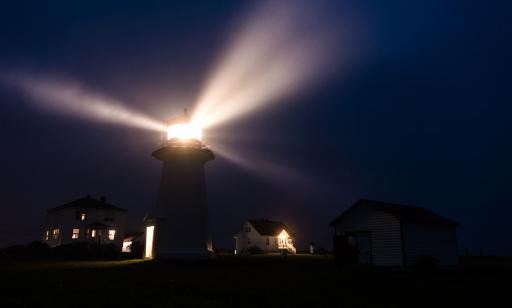 Durant une nuit chargée d’humidité, on voit les rayons de lumière d’un phare se dissiper dans les fines gouttelettes d’eau.