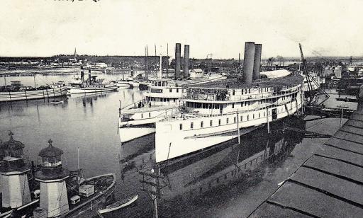 View of two boats, each with a small octagonal tower amidships. Many other vessels crowd the water. 