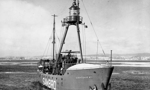 A ship bearing a lantern held up by a tripod, sailing through floating ice on the river.